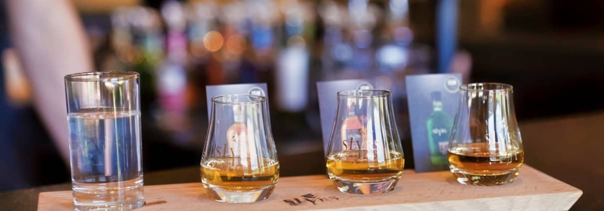 Drei Probiergläser mit SLYRS Whisky in unterschiedlichen Farbnuancen an der Bar.