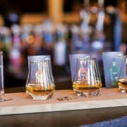 Drei Probiergläser mit SLYRS Whisky in unterschiedlichen Farbnuancen an der Bar.