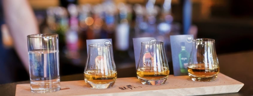 Drei Probiergläser mit SLYRS Whisky in unterschiedlichen Farbnuancen an der Bar.